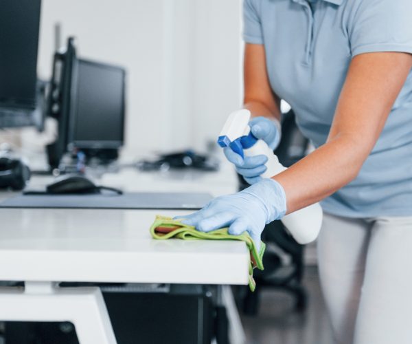 Close up view of woman in protective gloves that cleaning tables in the office Close up view of woman in protective gloves that cleaning tables in the office