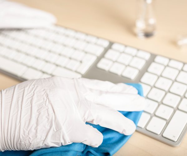 Hand with gloves cleaning a keyboard with disinfectant Hand with gloves cleaning a keyboard with disinfectant